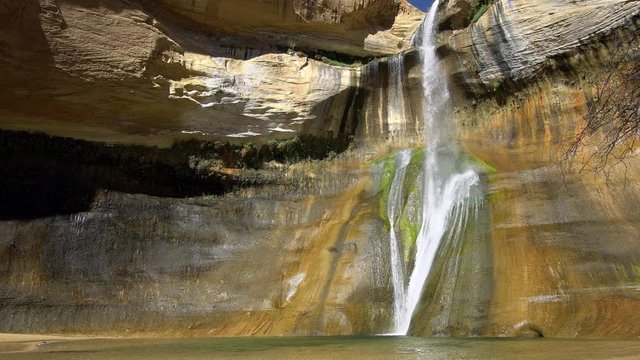 Lower Calf Creek Falls in Escalante Utah flowing down colorful cliffs.