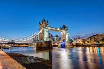 The Tower Bridge in London at night with the City in the back