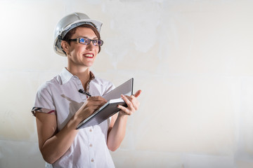 Cute young woman in white construction protection building helmet in unfinished apartment © keleny