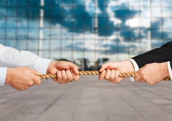 Tug war, two businessman pulling a rope in opposite directions