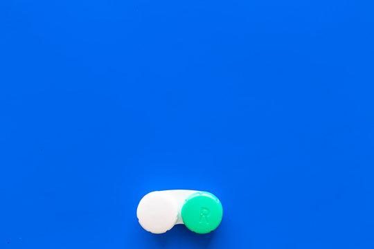 Improve vision concept. Contact lenses in container on blue background top view copy space