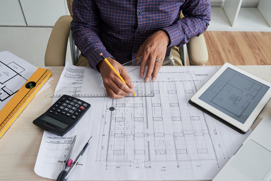 Cropped image of engineer measuring details on house blueprint
