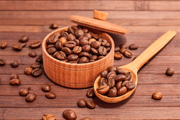Coffee composition on a wooden background. Grains of coffee in a wooden jar. Lattice coffee beans close-up on a wooden surface. Coffee beans.