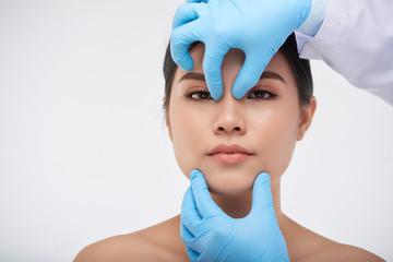 Hands of surgeon checking face construction of young Asian woman