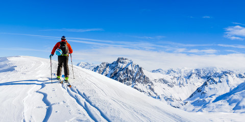 Naklejka na ściany i meble Ski in winter season, mountains and ski touring man on the top in sunny day in France, Alps above the clouds.