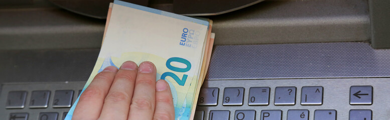 hand takes european banknotes at ATM