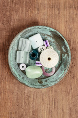 An overhead photo of various beads in a small teal blue plate, with copy space