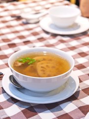 Chinese Lotus Root soup in a white bowl on red checked Pattern tablecloth