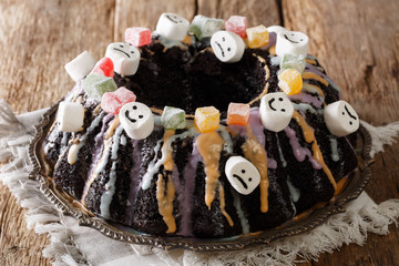 beautiful Bundt cake richly decorated with candied fruits, marshmallow and colorful glaze close-up. horizontal
