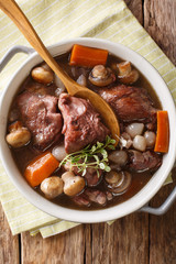 French cuisine: Coq au vin cock in wine close-up in a bowl. Vertical top view from above