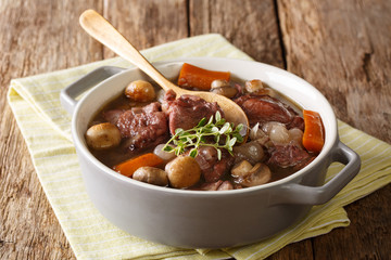 Coq au vin - french food slowly cooked cock with wine and vegetables close-up in a pot. horizontal