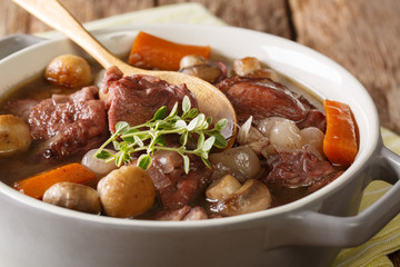 Traditional French food: Coq au vin cock with wine and vegetables, thyme close-up in a pot. horizontal