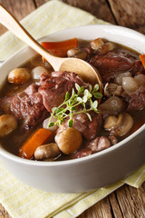 French cuisine: Coq au vin cock in wine close-up in a bowl. vertical