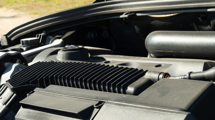 View of powerful car gasoline Internal combustion engine with many details over the hood, a system of interconnected parts that makes it possible to move, sunny day and sand on the background