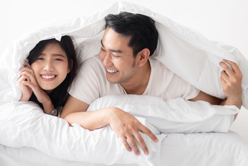 Happy Asian couple under white blanket together, lifestyle concept.