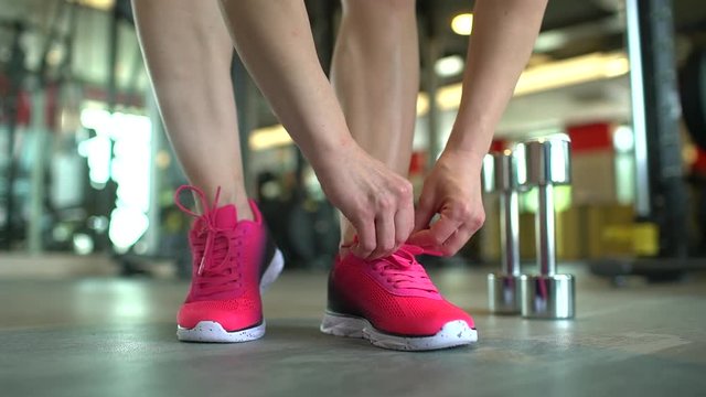 Healthy woman getting ready for gym workout tying pink shoe laces. The concept of sport, beauty, fitness, healthy lifestyle, beautiful body, health, bodybuilding, training routine, proper nutrition