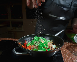 Caucasian chief cook cooking on the wok pan with flambe on the asian restaurant kitchen