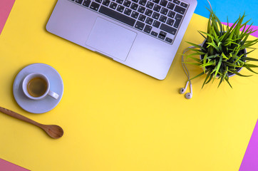 Laptop and headphones with coffee and plant on yellow, blue and purpure background. Morning. Flat lay. Top view. Copy space