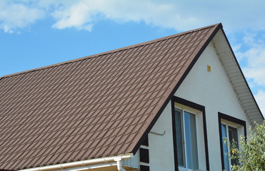 Attic house with metal roof and white plastic rain gutter.
