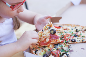 young girl eat delicious italian pizza from cardboard box