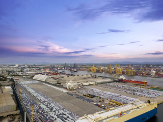 Aerial view of logistics concept commercial vehicles, cars and pickup trucks waiting to be load on to a roll-on/roll-off car carrier ship at Laem Chabang dockyard in Chonburi Province, Thailand
