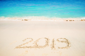 Fototapeta na wymiar Inscription on the sand, celebrate the new year in the tropics. New year holidays