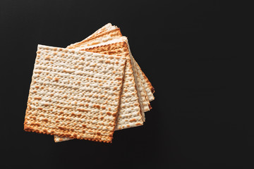 A photo of matzah or matza pieces  on black background. Matzah for the Jewish Passover holidays. Place for text, copy space