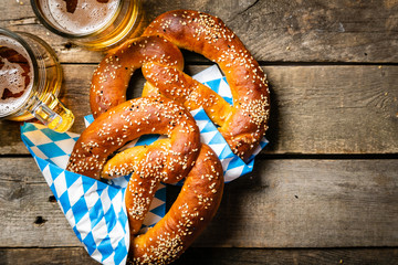 Oktoberfest concept - pretzels and beer on rustic wood background, top view