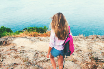 back view blonde girl backpacker standing shore island