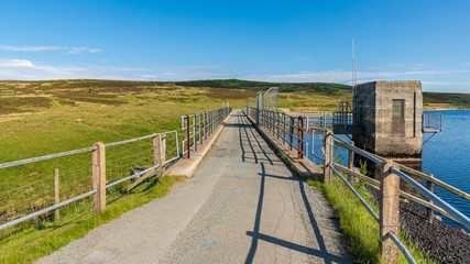 Fototapeta premium Rural road in Wales, leading over the dam at the Aled Isaf Reservoir, Conwy, Wales, UK