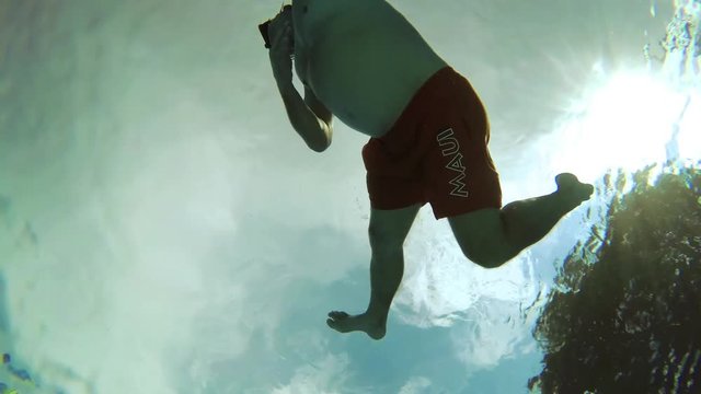 The teenager swims in the pool under the water.