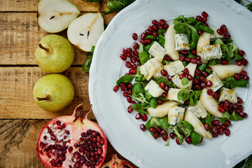 delicious salad of pear gorgonzola cheese and lettuce on a white plate on a wooden table