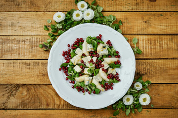flowers and a delicious salad of pear gorgonzola cheese and lettuce on a white plate on a wooden table