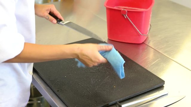 A food service worker or chef sanitizing (disinfecting) a knife in a commercial kitchen.  A food safet concept