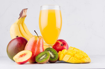 Summer fresh drink of tropical fruits with ripe sliced mango, kiwi and banana on white wood table, closeup.