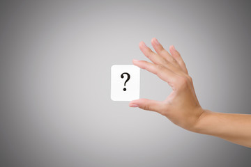 Woman's hand showing card of question mark on gray background. Solution search concept.