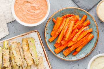 Set of baked season vegetable sticks of zucchini and carrots with sauce and hummus. Vegetarian healthy food. Flat lay, top view.