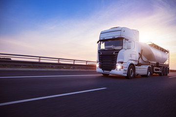 Loaded European truck tank on motorway in beautiful sunset light. On the road transportation and...