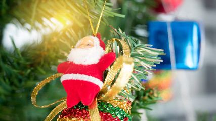 Christmas decorations focusing on red gift box hanging on pine tree with bokeh of blinking led on background..