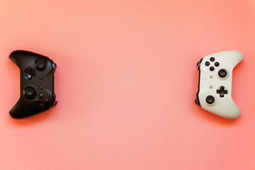 White and black two joystick gamepad, game console on pink colourful trendy modern fashion pin-up background. Computer gaming competition videogame control confrontation concept
