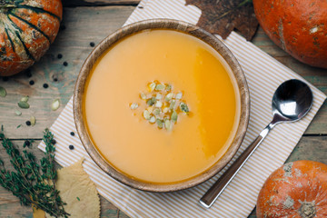 Bowl of pumpkin soup on rustic wooden background