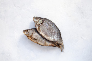 Two dried fish carp on a white concrete background
