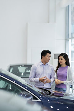 Vietnamese Couple Choosing Nice Car In Showroom