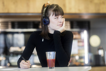 Junge Frau im Cafe mit Kopfhörer bluetooth