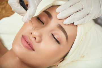 Obraz na płótnie Canvas Face of attractive Vietnamese woman getting vacuum cleansing procedure