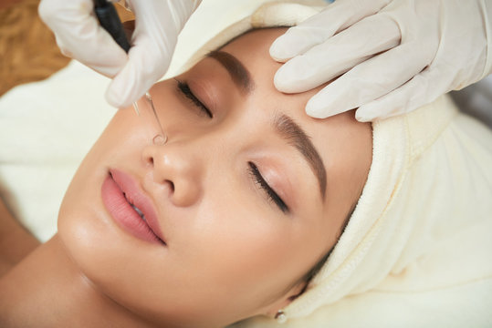 Face of attractive Vietnamese woman getting vacuum cleansing procedure