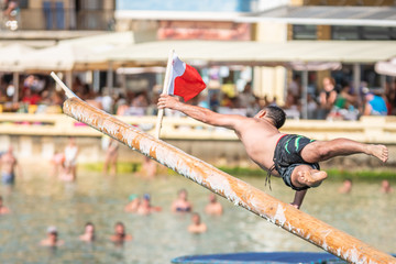 Greasy pole, maltese flags. xlendi bay Gozo feast. man jump catch the flag.