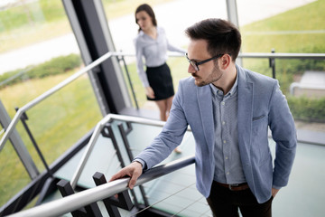 Modern business people walking on stairs in glass hall in office building