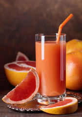 Glass of fresh grapefruit juice and cut fruits .