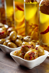 Spiced green olives and bottles with olive oil .